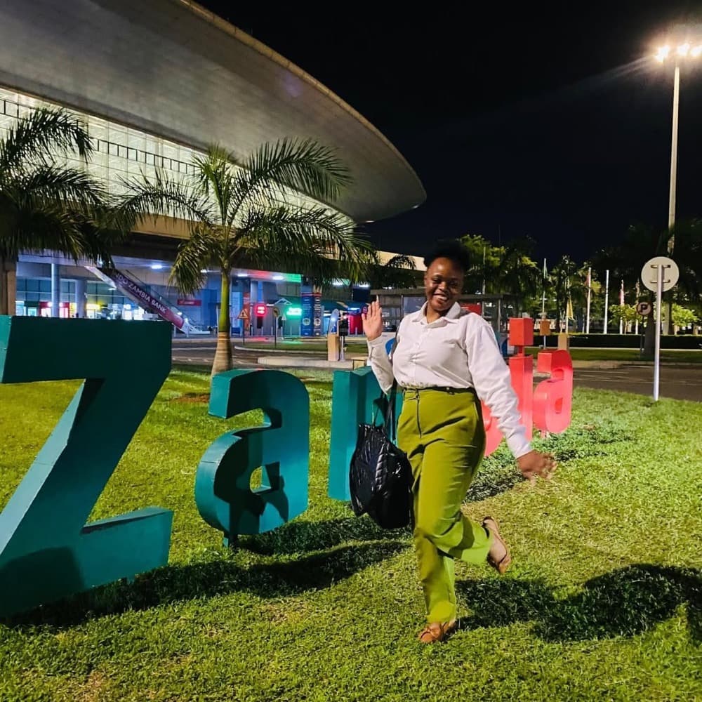 A person posing beside the large Zambia sign at night